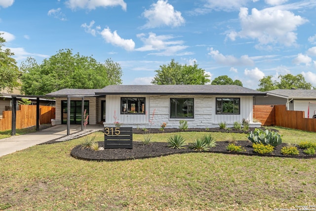 view of front facade featuring concrete driveway, fence, board and batten siding, and a front yard