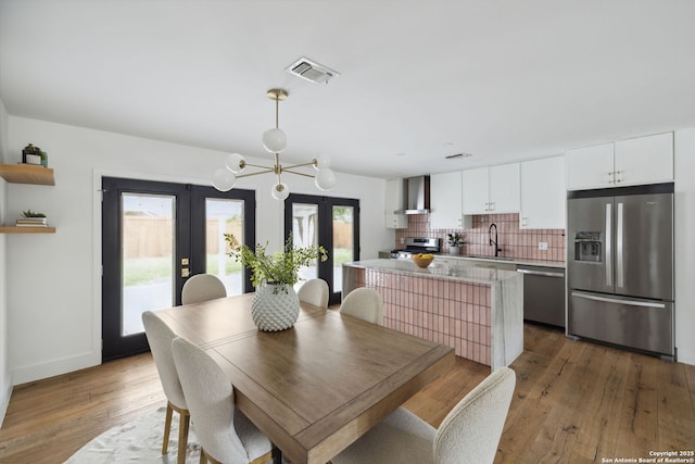 dining space with a notable chandelier, french doors, hardwood / wood-style floors, baseboards, and visible vents