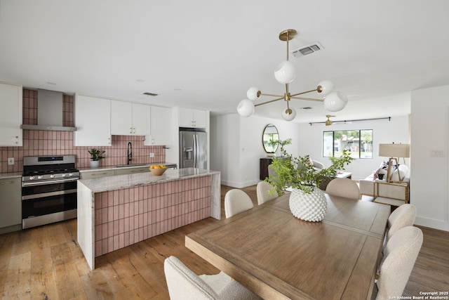 dining room with visible vents, light wood finished floors, baseboards, and a chandelier