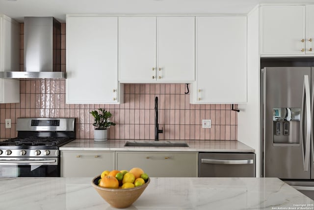 kitchen featuring a sink, appliances with stainless steel finishes, wall chimney exhaust hood, and white cabinetry