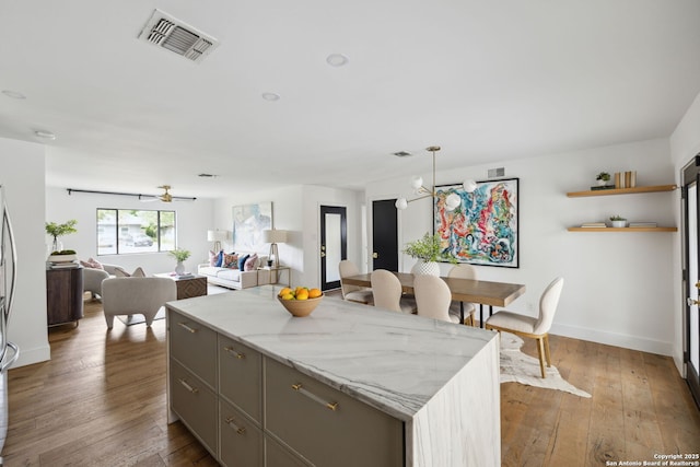 kitchen with wood-type flooring, gray cabinets, open floor plan, baseboards, and visible vents