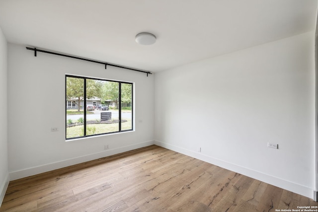 empty room with baseboards and light wood-type flooring