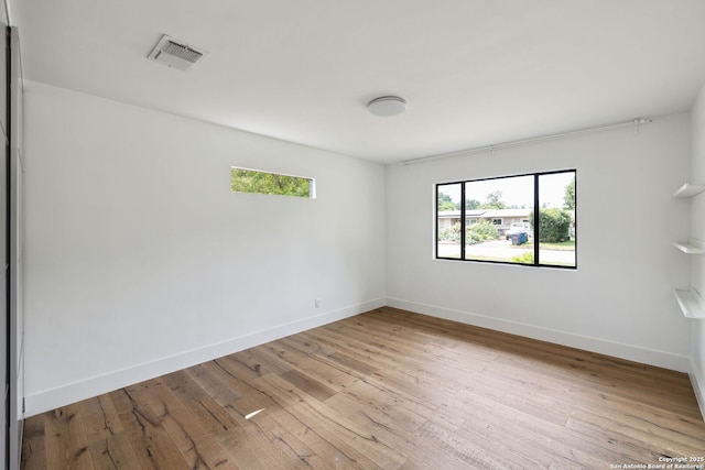 spare room with wood-type flooring, baseboards, and visible vents