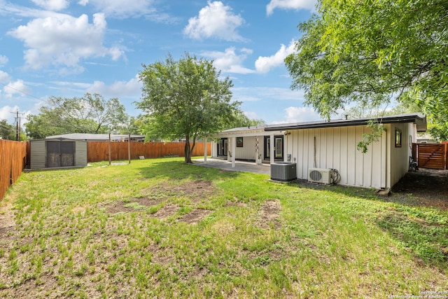 view of yard with an outbuilding, ac unit, a shed, a fenced backyard, and a patio