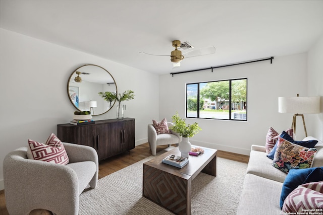 living area with baseboards, ceiling fan, visible vents, and wood finished floors