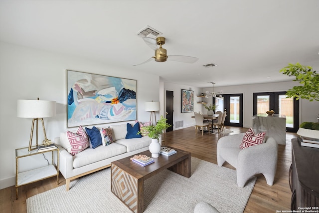 living room with visible vents, wood finished floors, and ceiling fan with notable chandelier