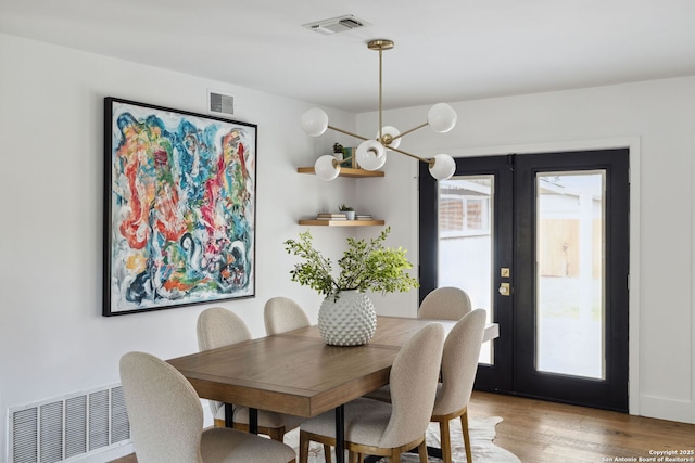 dining room featuring french doors, wood finished floors, and visible vents