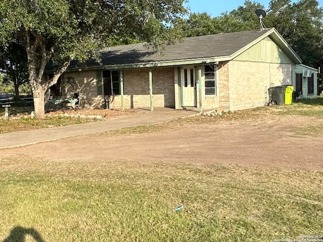 ranch-style house featuring brick siding, a front yard, and dirt driveway