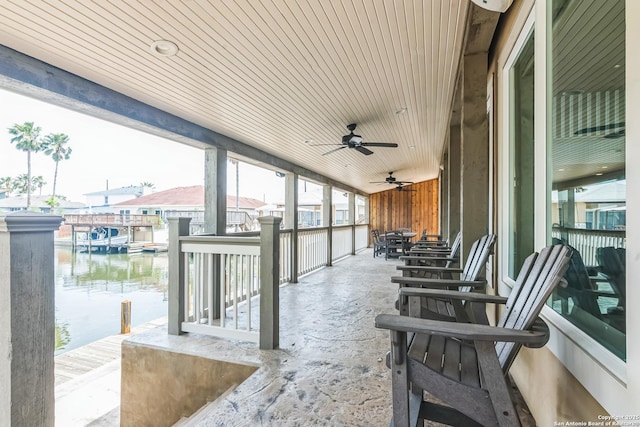 view of patio with a water view, a dock, and ceiling fan