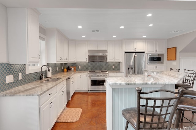 kitchen with a sink, white cabinetry, a kitchen bar, and high quality appliances