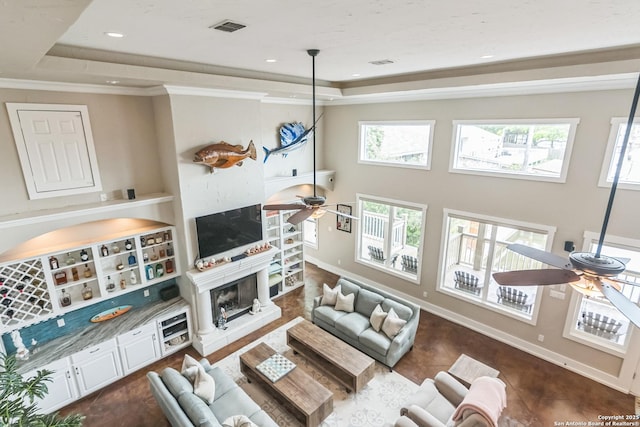 living area featuring ceiling fan, visible vents, a wealth of natural light, and a tray ceiling