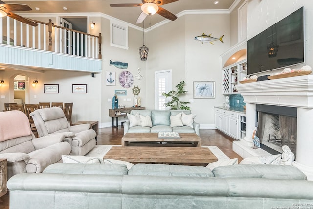 living room with ceiling fan, ornamental molding, baseboards, and a towering ceiling