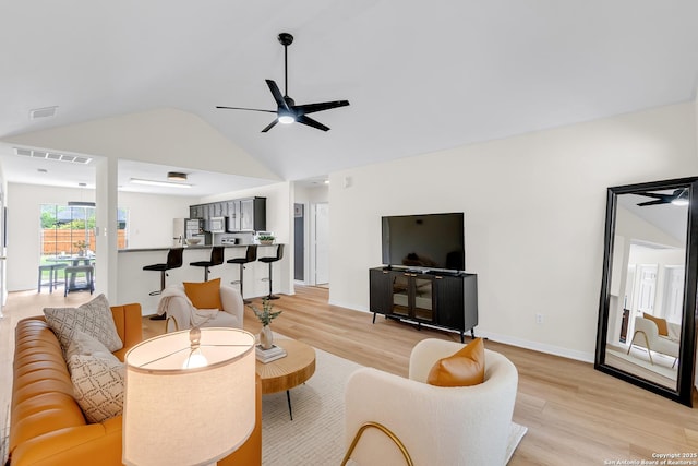 living room with light wood-type flooring, a ceiling fan, vaulted ceiling, and visible vents