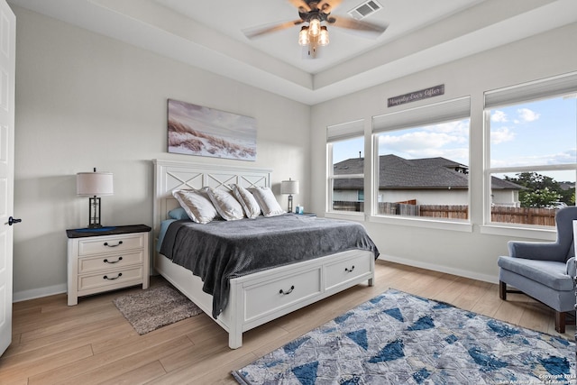 bedroom with visible vents, a ceiling fan, light wood finished floors, and baseboards