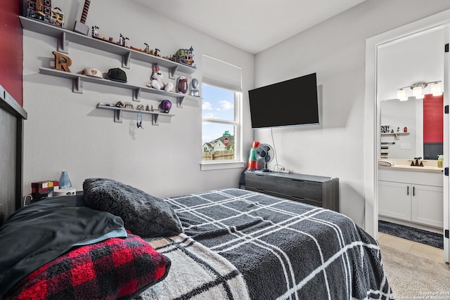 bedroom featuring connected bathroom, a sink, and light tile patterned floors