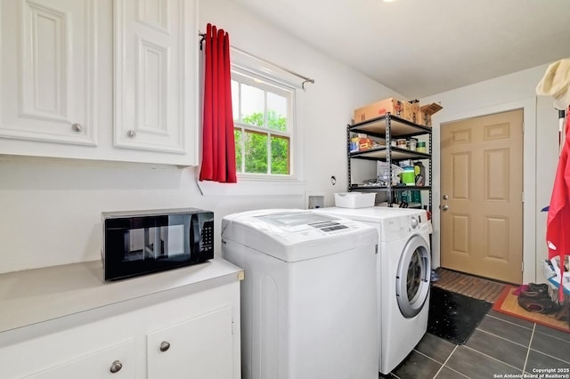 washroom featuring dark tile patterned flooring, washing machine and dryer, and cabinet space