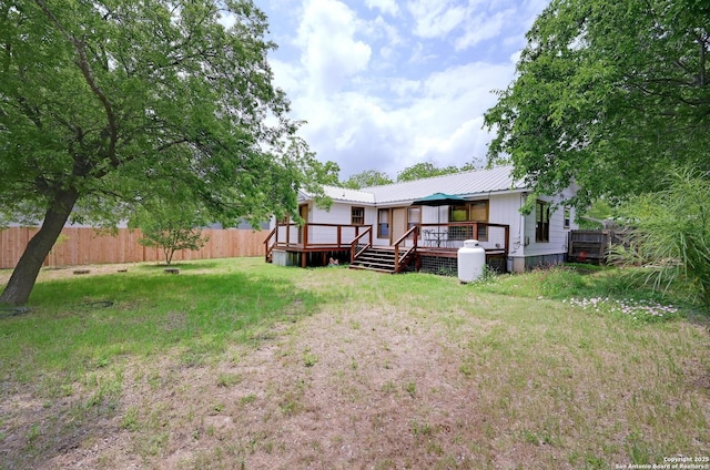 back of property with a fenced backyard, a yard, a deck, and metal roof