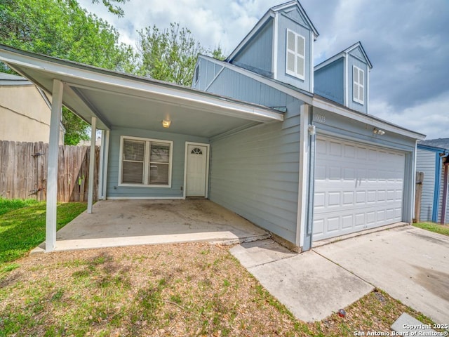 view of front of property featuring fence, driveway, and a garage