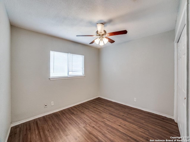 unfurnished bedroom featuring baseboards, a ceiling fan, a closet, and dark wood-type flooring
