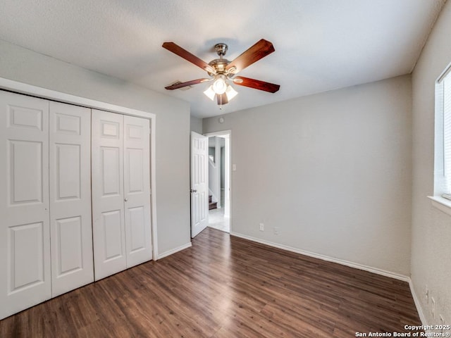 unfurnished bedroom featuring baseboards, ceiling fan, a closet, and wood finished floors