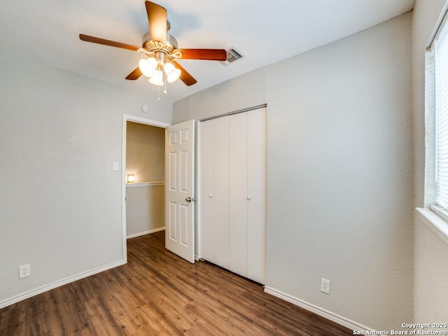 unfurnished bedroom featuring baseboards, a closet, wood finished floors, and visible vents