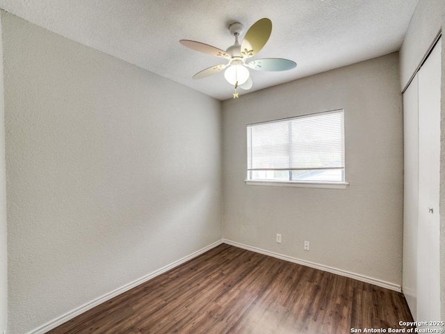 empty room featuring dark wood-type flooring, baseboards, and ceiling fan