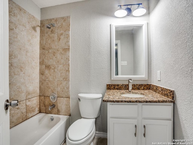 bathroom featuring vanity, a textured wall, shower / tub combination, and toilet