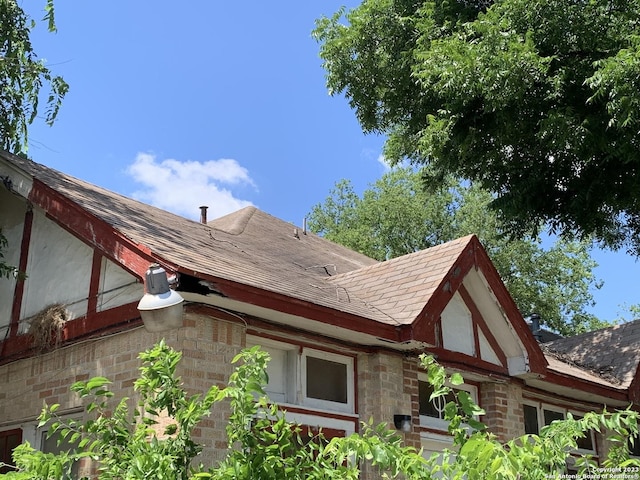 view of side of property with brick siding and a shingled roof