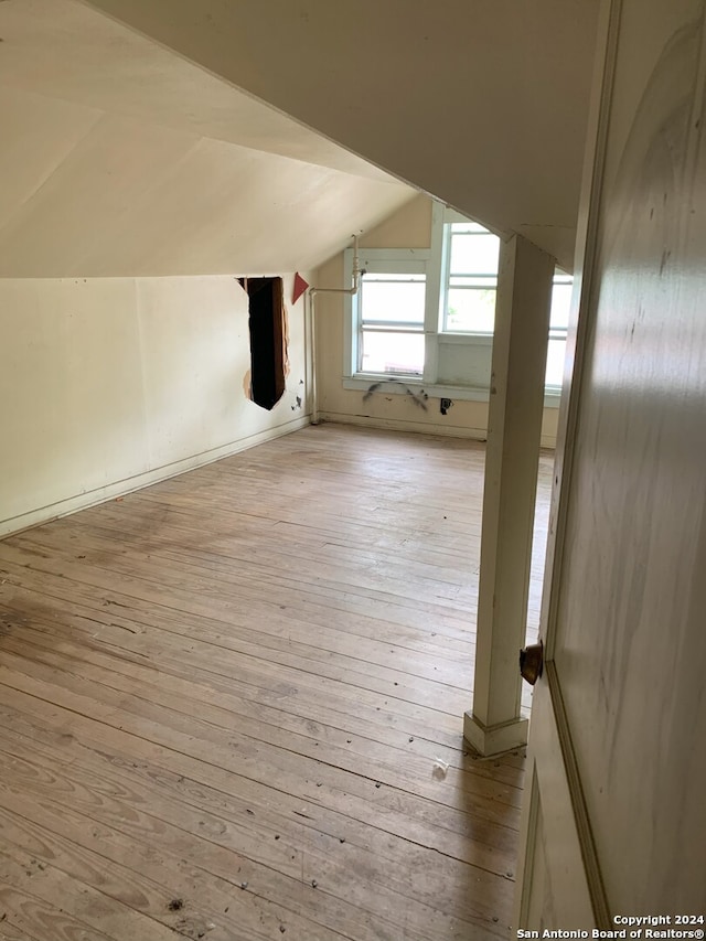 additional living space featuring vaulted ceiling and light wood-type flooring