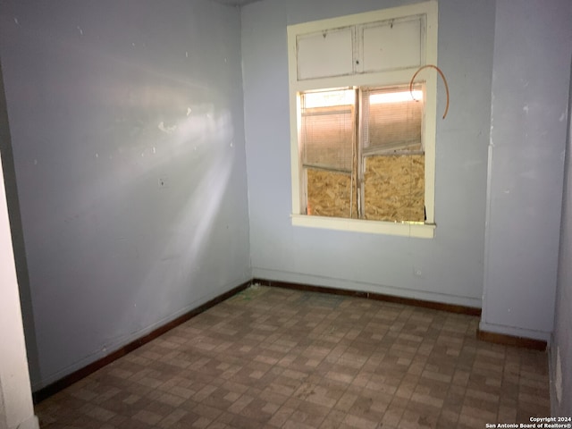 unfurnished room with baseboards and brick patterned floor