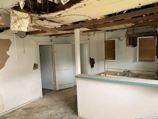 interior space featuring a sink, a peninsula, and unfinished concrete flooring