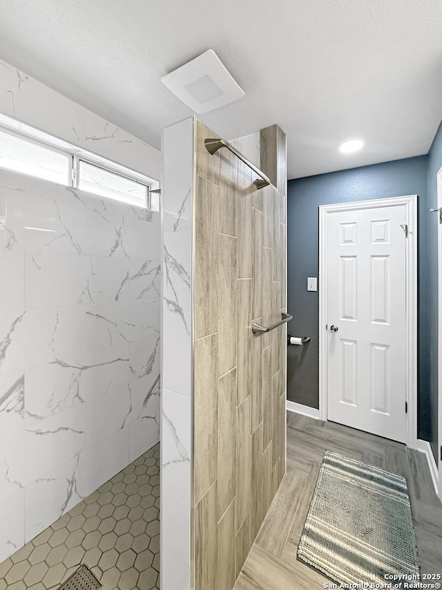 bathroom with a textured ceiling and a marble finish shower