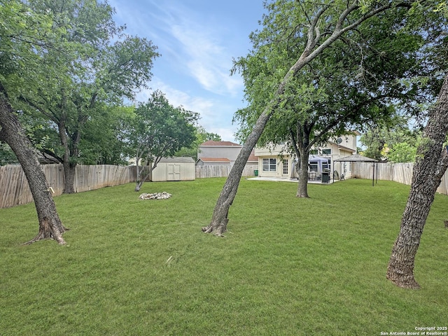 view of yard featuring an outdoor structure, a fenced backyard, and a storage shed