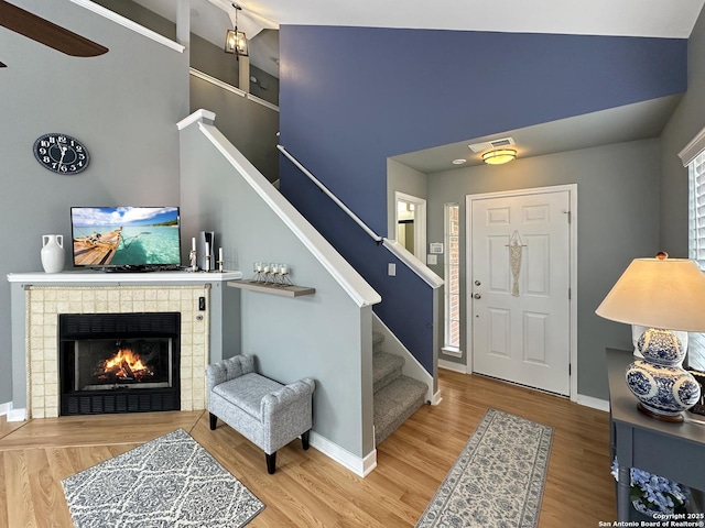 foyer with baseboards, stairs, wood finished floors, and a fireplace