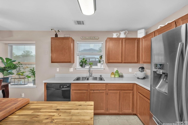kitchen featuring a sink, black dishwasher, a healthy amount of sunlight, and stainless steel fridge with ice dispenser