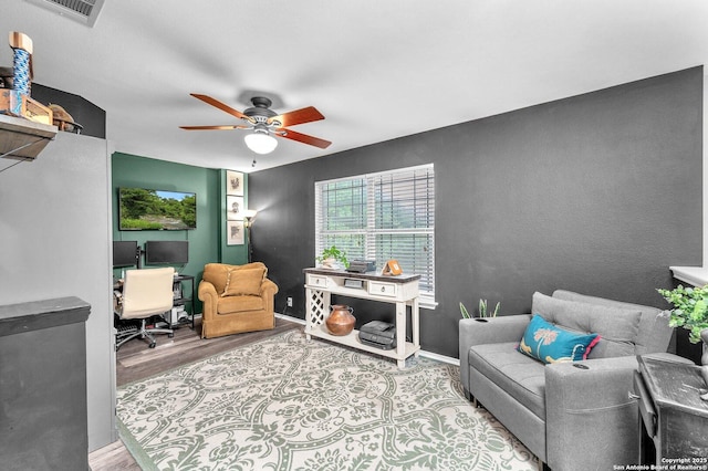 interior space featuring a ceiling fan, baseboards, visible vents, and wood finished floors
