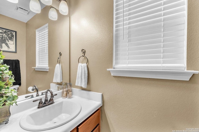 bathroom with vanity, a textured wall, and visible vents