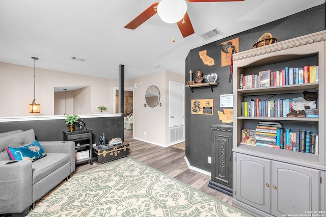 living room featuring visible vents, baseboards, ceiling fan, and wood finished floors