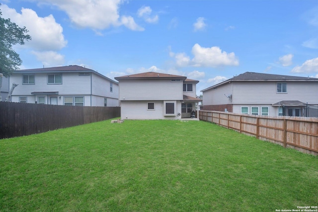 rear view of house featuring a fenced backyard and a yard