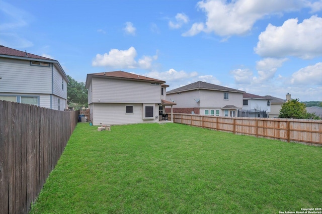 rear view of house featuring a fenced backyard and a lawn