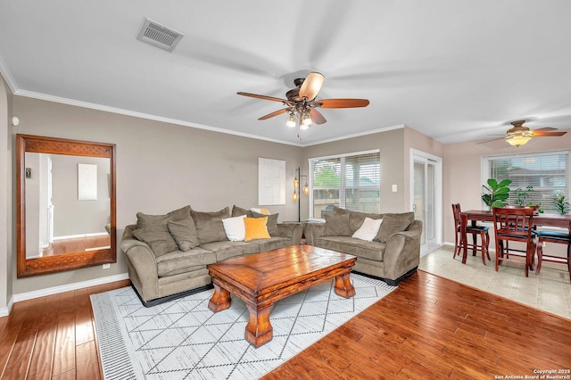 living area with visible vents, light wood-style flooring, ceiling fan, and baseboards