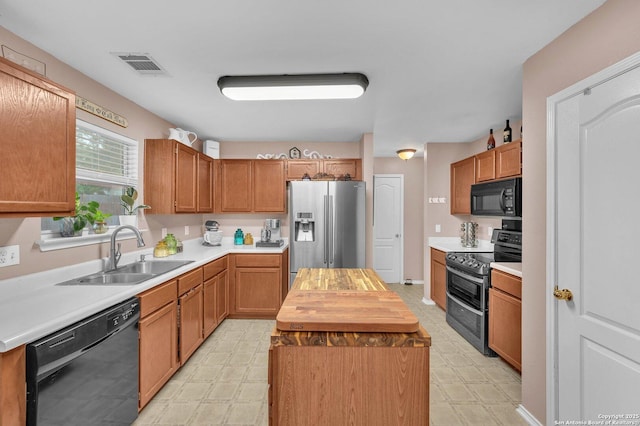 kitchen featuring a sink, butcher block countertops, light floors, visible vents, and black appliances