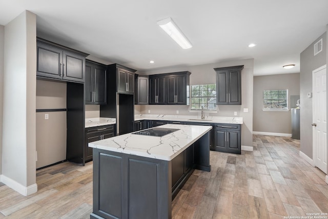 kitchen featuring a sink, a center island, baseboards, light wood-type flooring, and visible vents