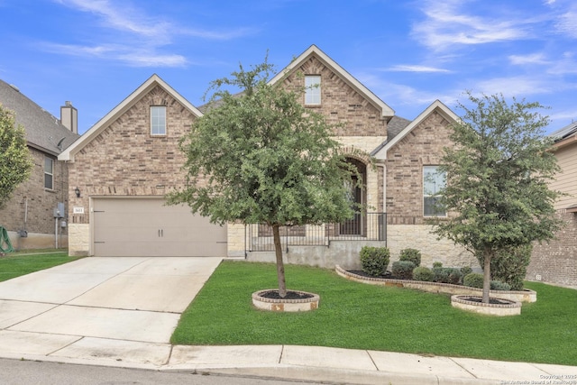traditional home with stone siding, a front yard, brick siding, an attached garage, and driveway