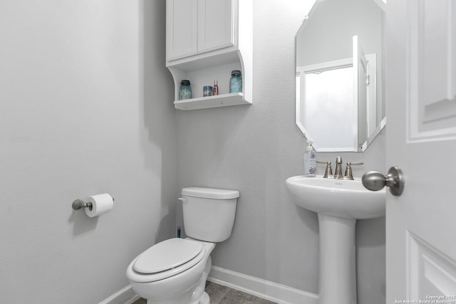 half bathroom featuring baseboards, tile patterned floors, and toilet