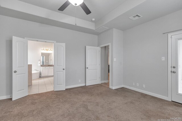 unfurnished bedroom featuring baseboards, light carpet, connected bathroom, and visible vents