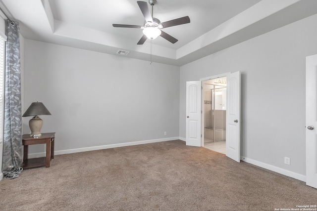 unfurnished bedroom with visible vents, baseboards, carpet floors, and a tray ceiling