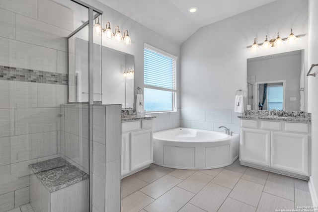 bathroom featuring a bath, vaulted ceiling, a stall shower, two vanities, and a sink