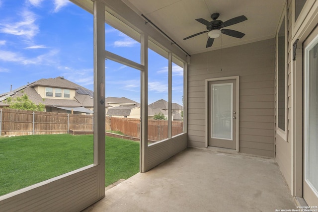 unfurnished sunroom with ceiling fan and a residential view