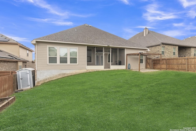 rear view of house featuring a storage shed, a yard, a fenced backyard, and a sunroom